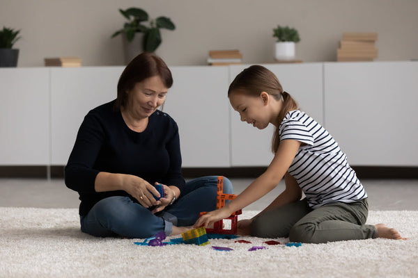 Happy,Elderly,Grandmother,And,Small,Teen,Granddaughter,Sit,On,Carpet