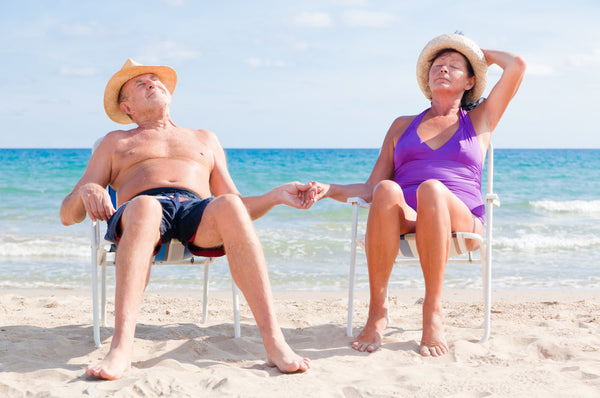 Happy,Retired,Senior,Couple,Sitting,On,The,Beach,Holding,Hands